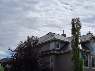 Deep Charcoal Interlock Slate aluminum roof on a tan single-family home with a modern style among urban, Calgary, Alberta