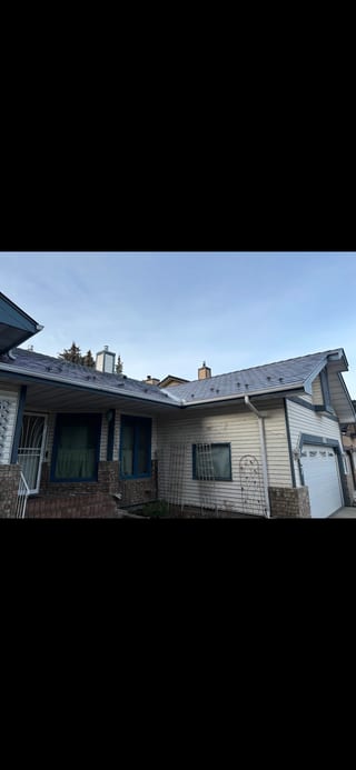 Musket Grey Interlock Slate aluminum roof on a beige single-family ranch home in the city under a blue, Calgary, Alberta