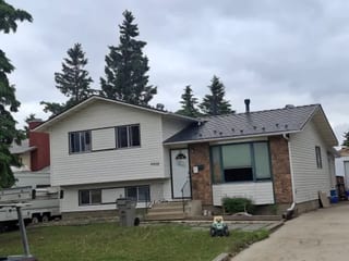 Deep Charcoal Interlock Cedar Shingle aluminum roof on a two-storey home with a metal roof among tall evergreens, Grande Prairie, Alberta