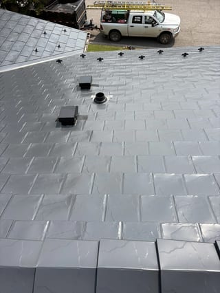 Deep Charcoal Interlock Slate aluminum roof on a modern home with a metal roof among rural fields, Coleman, Alberta