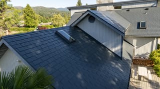 Deep Charcoal Interlock Slate aluminum roof on a two-storey home with a metal roof in a forested mountain, Sechelt, British Columbia