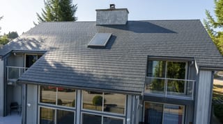 Deep Charcoal Interlock Slate aluminum roof on a two-storey home with grey siding and a metal roof in, Sechelt, British Columbia