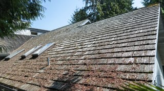 Deep Charcoal Interlock Slate aluminum roof on a grey home with dormers among evergreen trees in Sechelt, Sechelt, British Columbia