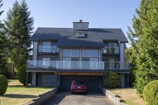 Deep Charcoal Interlock Slate aluminum roof on a two-storey home with a balcony and a red car in the garage, Sechelt, British Columbia