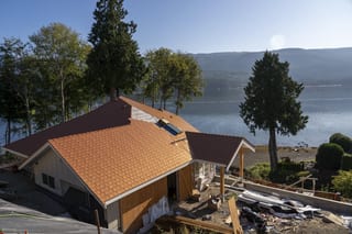 Copper Penny Interlock Slate aluminum roof being installed on a brown house with copper roof and dormers on a waterfront, Sechelt, British Columbia