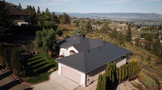 Deep Charcoal Interlock Slate aluminum roof on a two-storey home with a metal roof in a mountain setting, West Kelowna, British Columbia