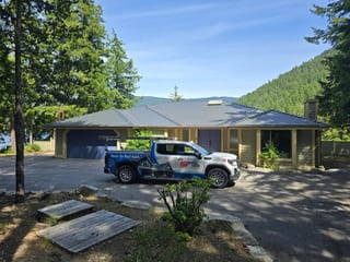 Deep Charcoal Interlock Slate aluminum roof on a yellow home with dormers among tall pines, Sechelt, British Columbia