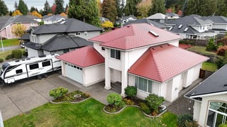 Tile Red Interlock Shingle aluminum roof on a white two-storey home with a red metal roof in a suburban, Surrey, British Columbia
