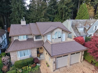 Colonial Brown Interlock Shake aluminum roof on a tan colonial home with dormers and garage amidst tall, North Vancouver, British Columbia