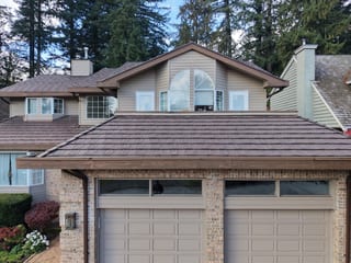 Colonial Brown Interlock Shake aluminum roof on a tan two-storey home with dormers in a forested urban area, North Vancouver, British Columbia