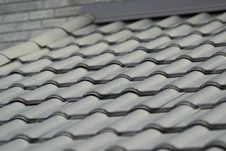 Before: a metal roof with broken tiles on the home, Surrey, British Columbia, ahead of a Black Interlock Slate aluminum roof