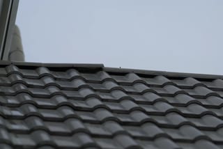 Before: a metal roof with broken tiles on the home, Surrey, British Columbia, ahead of a Black Interlock Slate aluminum roof