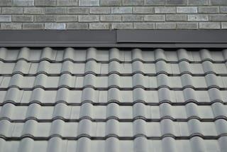 Before: a metal roof with broken tiles on the home, Surrey, British Columbia, ahead of a Black Interlock Slate aluminum roof