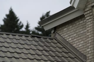 Before: a metal roof with broken tiles on the home, Surrey, British Columbia, ahead of a Black Interlock Slate aluminum roof