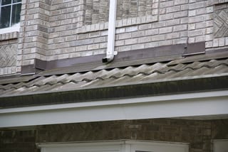 Before: a metal roof with broken tiles on the home, Surrey, British Columbia, ahead of a Black Interlock Slate aluminum roof