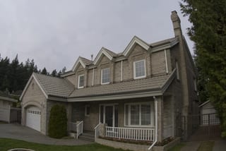 Before: a metal roof with broken tiles on the home, Surrey, British Columbia, ahead of a Black Interlock Slate aluminum roof