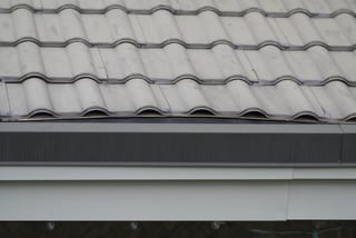 Before: a metal roof with broken tiles on the home, Surrey, British Columbia, ahead of a Black Interlock Slate aluminum roof
