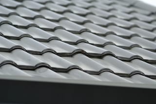 Before: a metal roof with broken tiles on the home, Surrey, British Columbia, ahead of a Black Interlock Slate aluminum roof