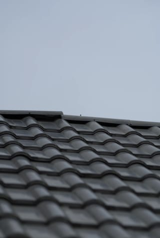 Before: a metal roof with broken tiles on the home, Surrey, British Columbia, ahead of a Black Interlock Slate aluminum roof