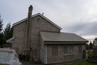 Before: a metal roof with broken tiles on the home, Surrey, British Columbia, ahead of a Black Interlock Slate aluminum roof