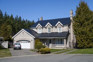 Black Interlock Slate aluminum roof on a tan brick home with a metal roof and black trim among, Surrey, British Columbia