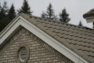 Before: the old roof on a two-storey modern home with a metal roof among tall trees, Surrey, British Columbia, ahead of a Black Interlock Slate aluminum roof