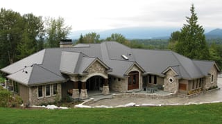 Charcoal Grey Interlock Slate aluminum roof on a stone ranch home with a metal roof in a forested mountain, Mission, British Columbia
