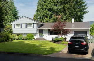 Weathered Interlock Slate aluminum roof on a white ranch home with a metal roof among tall trees, Burnaby, British Columbia