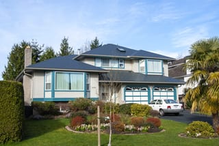 Deep Charcoal Interlock Slate aluminum roof on a beige two-storey home with a garage and palm trees, Surrey, British Columbia