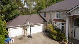 Tudor Brown Interlock Slate aluminum roof on a Tudor-style home with a brown metal roof in a forested, Surrey, British Columbia