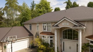 Tudor Brown Interlock Slate aluminum roof on a two-storey Tudor home with a brown metal roof in a, Surrey, British Columbia