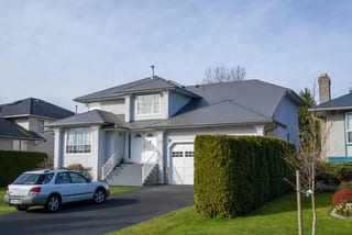 Musket Grey Interlock Slate aluminum roof on a two-storey home with a grey metal roof in a lush green, Surrey, British Columbia