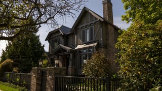 Deep Charcoal Interlock Slate aluminum roof on a brown two-storey craftsman home with dormers among tall, Vancouver, British Columbia