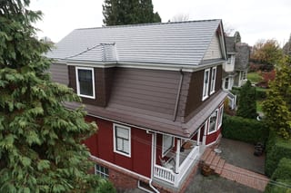 Colonial Brown Interlock Cedar Shingle aluminum roof on a red two-storey home with Colonial style in an urban area, New Westminster, British Columbia