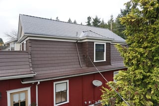 Colonial Brown Interlock Cedar Shingle aluminum roof on a red colonial home with dormers in a forested area, New Westminster, British Columbia