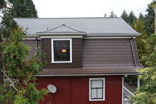 Colonial Brown Interlock Cedar Shingle aluminum roof on a brown colonial home with dormers in a forested area, New Westminster, British Columbia