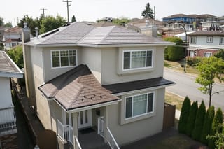 Aerial front view of a 2-storey stucco home in Vancouver with a complex multi-hip Interlock aluminum slate roof in Colonial Brown.
