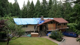 Deep Charcoal Interlock Slate aluminum roof on a brown chalet-style home with a metal roof in the forest, Anmore, British Columbia