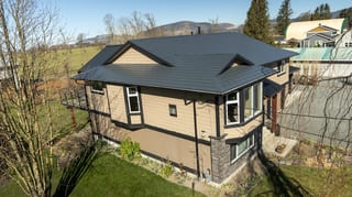 Deep Charcoal Interlock Slate aluminum roof on a tan single-family home with a metal roof in a rural, Abbotsford, British Columbia