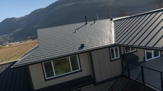 Deep Charcoal Interlock Slate aluminum roof on a tan one-storey home with a metal roof in a mountain, Abbotsford, British Columbia