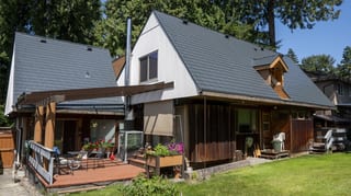 Deep Charcoal Interlock Slate aluminum roof on a white A-frame home with dormers among tall trees, Burnaby, British Columbia