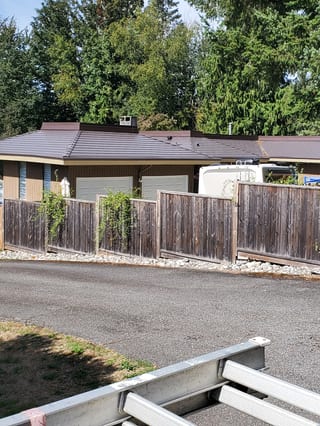 Tudor Brown Interlock Cedar Shingle aluminum roof on a brown one-storey home with a metal roof in a wooded area, Mission, British Columbia