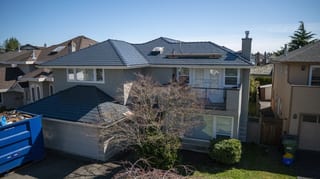 Deep Charcoal Interlock Slate aluminum roof on a grey single-family home with a balcony in a suburban, Richmond, British Columbia