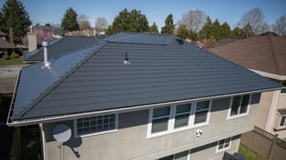 Deep Charcoal Interlock Slate aluminum roof on a two-storey home with dormers in a suburban setting, Richmond, British Columbia