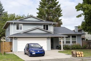 Deep Charcoal Interlock Slate aluminum roof on a gray two-storey home with a metal roof in a forested, Richmond, British Columbia