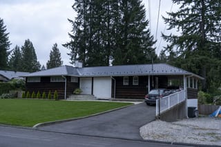 Deep Charcoal Interlock Slate aluminum roof on a brown ranch-style home with a metal roof among tall, North Vancouver, British Columbia