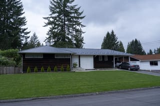 Deep Charcoal Interlock Slate aluminum roof on a brown ranch style home with a metal roof among tall trees, North Vancouver, British Columbia