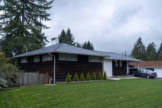 Deep Charcoal Interlock Slate aluminum roof on a dark house with a metal roof in a forested suburban, North Vancouver, British Columbia