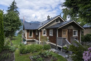 Black Interlock Slate aluminum roof on a brown cottage with a dark metal roof in a lush green, Britannia Beach, British Columbia