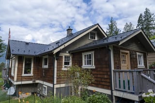 Black Interlock Slate aluminum roof on a brown, one-storey home with a metal roof among trees, Britannia Beach, British Columbia